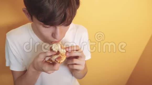 披萨快乐的生活方式青少年男孩吃一片披萨的概念十几岁的男孩饿了吃一片披萨慢动作视频的预览图