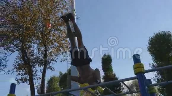 强壮的肌肉男在公园里做倒立适合肌肉发达的男性健身者在户外的横杠上做特技视频的预览图