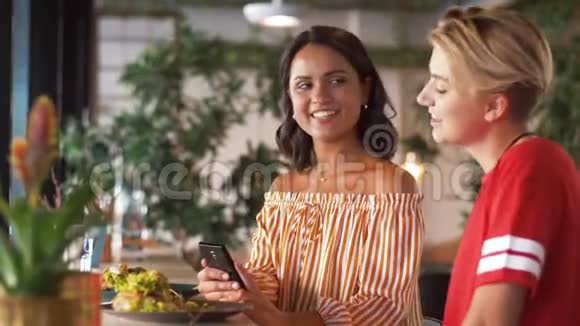 在餐馆有智能手机的女性朋友视频的预览图