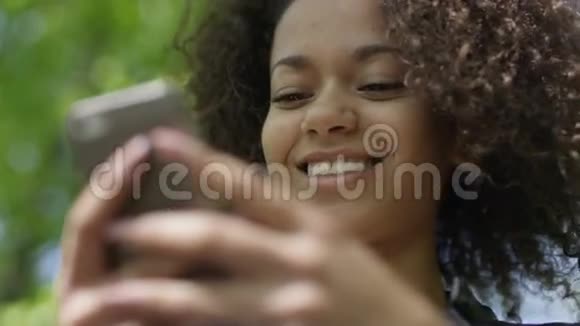 美丽的年轻女孩深色卷发使用她的手机户外视频的预览图