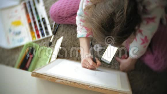 年轻的女画家在家坐在地板上创作绘画视频的预览图