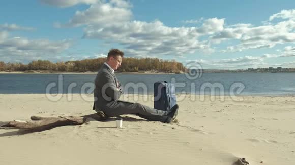 一个带手提笔记本手提箱的商人在海滩上放松视频的预览图