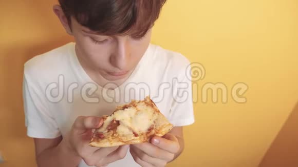 披萨快乐的青少年男孩吃一片生活方式的披萨概念小男孩饿了吃一片披萨慢动作视频的预览图