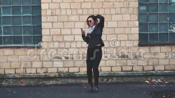 女人在街上的砖工业建筑的墙边跳舞视频的预览图