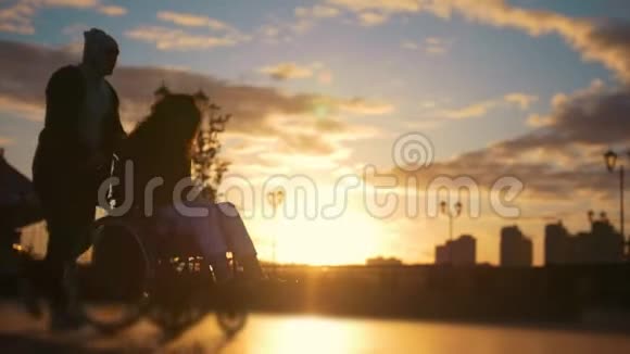 在日落时分一位坐在轮椅上的残疾女子在码头上行走视频的预览图
