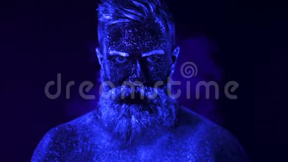 烟雾中紫外线照射下的蓄须男子的肖像视频的预览图