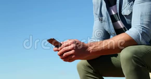阳光明媚的一天男人用手机视频的预览图
