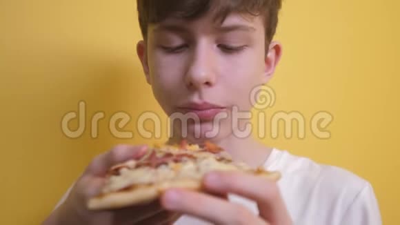 快乐的小男孩吃一片披萨的概念十几岁的男孩饥饿的生活方式吃一片披萨慢速视频视频的预览图