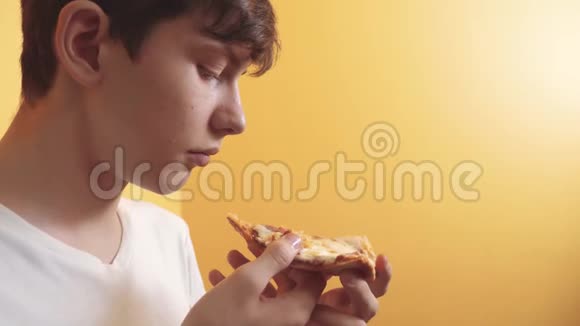 披萨快乐的小男孩吃一片披萨的概念饥饿的青少年男孩吃一片生活方式的披萨慢动作视频的预览图