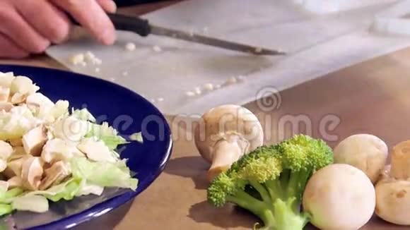 男人准备晚餐沙拉切莴苣和新鲜蔬菜用刀视频的预览图