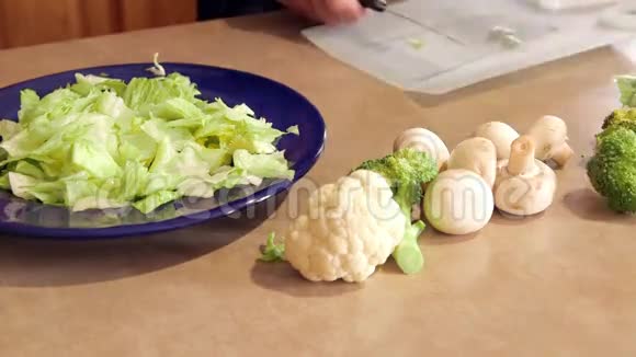 男人准备晚餐沙拉切莴苣和新鲜蔬菜用刀视频的预览图