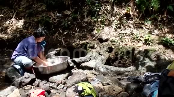 菲律宾农村社区缺乏公共供水系统设施迫使这名妇女即使在污染的河流中也要洗衣服视频的预览图