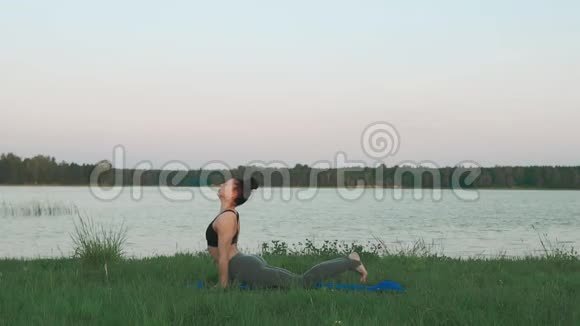 年轻女子早上在蓝色瑜伽垫上做瑜伽安静的风景视频的预览图