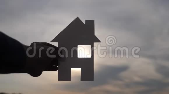 幸福家庭建设住宅理念男人手里拿着一个纸房子他的生活方式日落剪影视频的预览图