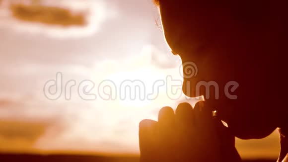 女孩祈祷女孩在日落时双手交叉祈祷剪影慢动作视频女孩的生活方式视频的预览图