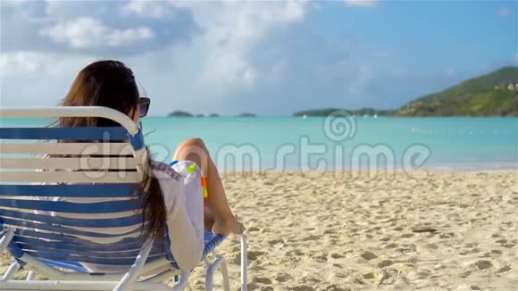 在热带白色海滩的休息室里晒日光浴的女人视频的预览图