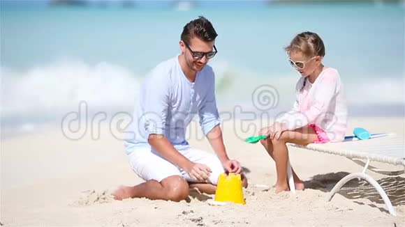 爸爸和小女儿在热带海滩做沙堡视频的预览图