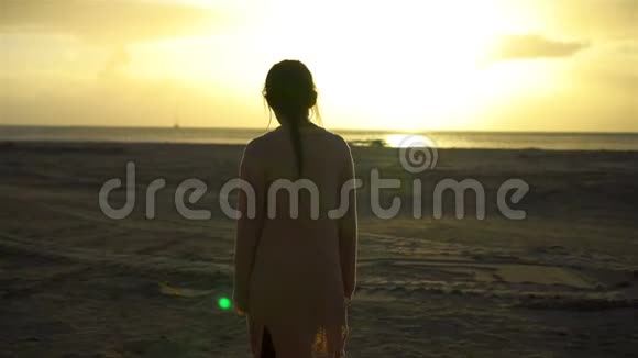 可爱的快乐小女孩在夕阳下的白色海滩散步视频的预览图