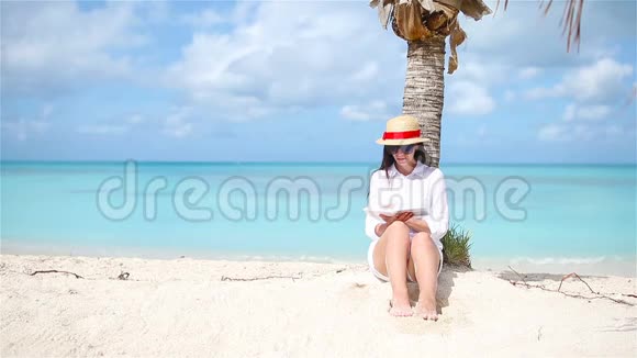 热带白海滩的年轻女子读书视频的预览图