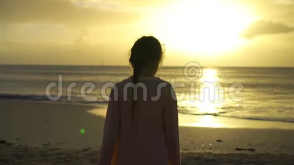 可爱的快乐小女孩在夕阳下的白色海滩散步视频的预览图
