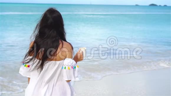 带着一杯茶在海滩上放松的年轻女子视频的预览图