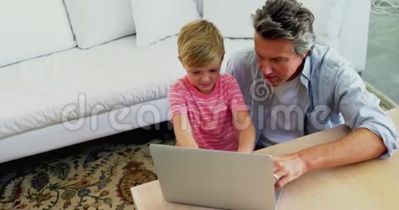 父亲和儿子在4k客厅用笔记本电脑视频的预览图