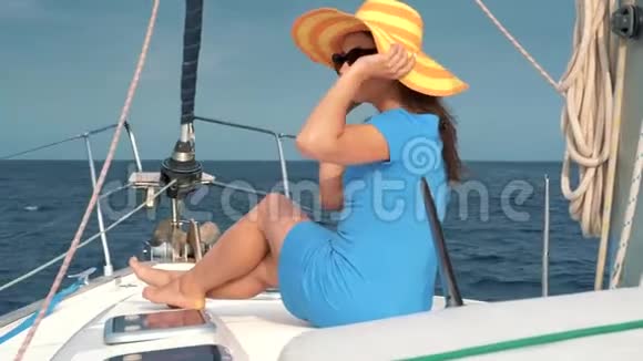 戴着黄色帽子的女人和穿着蓝色衣服的女孩在海洋的夏季在游艇上休息视频的预览图