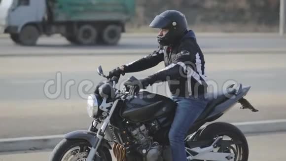 年轻迷人的摩托车手带着黑色头盔在街上骑摩托车的人视频的预览图