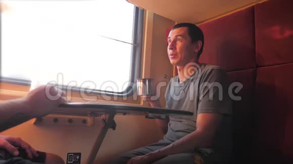 男人坐在火车车厢上手里拿着智能手机铁路喝着咖啡和茶慢生活方式慢生活方式视频的预览图