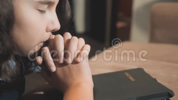 小女孩在夜里祈祷小女孩用手祈祷小女孩圣经祈祷与圣经在她的手中a视频的预览图