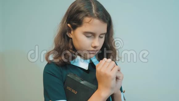 小女孩用手中的圣经祈祷天主教神圣圣经儿童和宗教教育视频的预览图