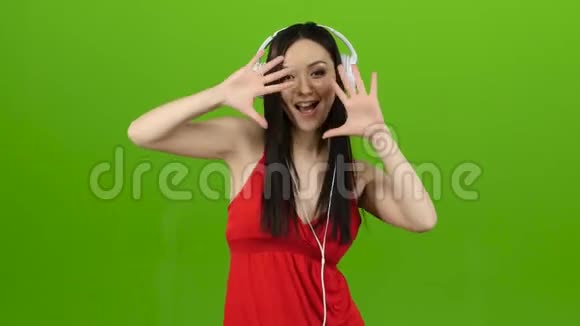 女孩通过耳机听欢快而充满活力的音乐绿色屏幕视频的预览图