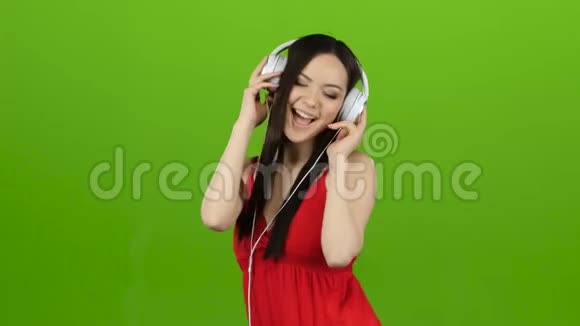 女孩通过耳机听欢快而充满活力的音乐绿色屏幕视频的预览图