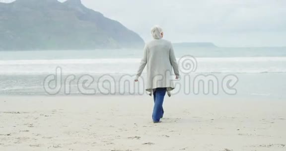 高级妇女在海滩散步的后景视频的预览图
