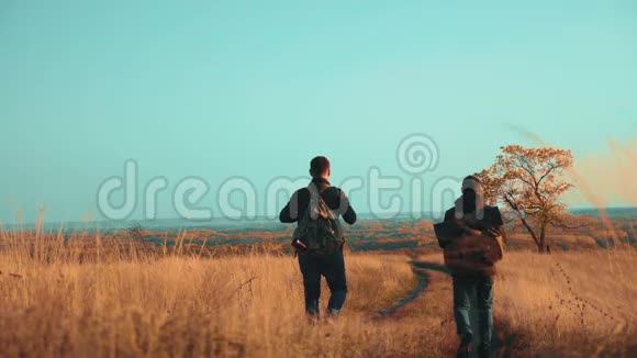 人们的生活方式游客在大自然中旅行秋天走在路上冒险慢动作视频两个徒步旅行者视频的预览图