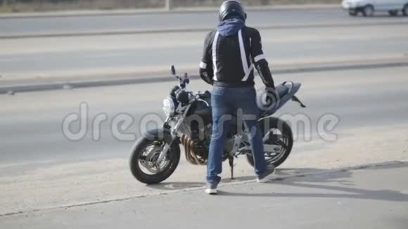 带着黑色头盔和运动摩托车的年轻有魅力男子摩托车手视频的预览图