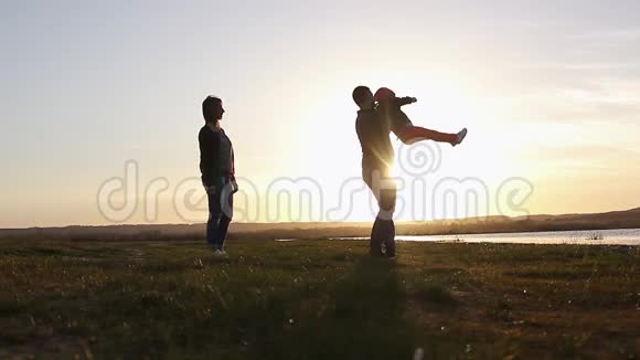 剪影和爸爸妈妈一起快乐的孩子日落时分的家人夏天奔跑在空中养育孩子拥抱爱玩耍视频的预览图