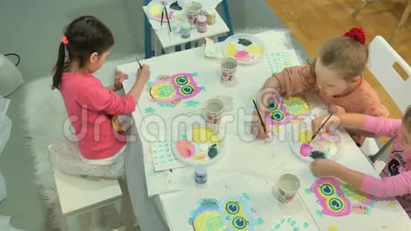 孩子们男孩和女孩在教室里围着桌子坐在一起画画视频的预览图