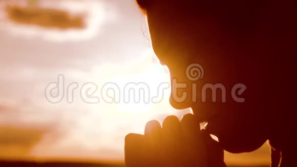 女孩祈祷女孩在日落时双手交叉祈祷剪影慢动作视频女孩的生活方式让她双手合拢视频的预览图