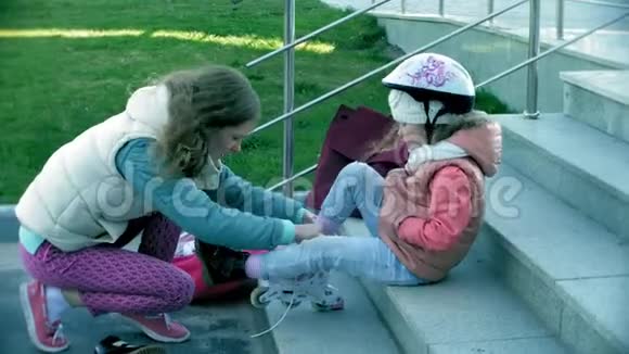 妈妈和女儿骑着溜冰鞋女孩学习溜冰摔倒妈妈教女儿骑车视频的预览图
