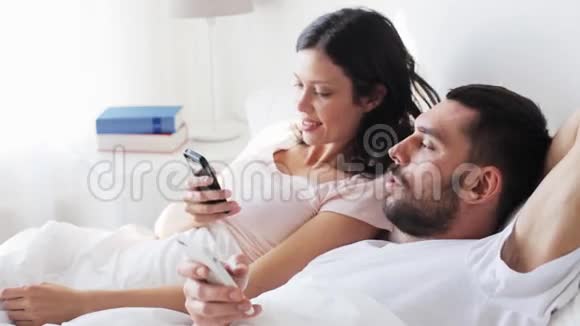 快乐的一对在床上有智能手机的夫妇视频的预览图