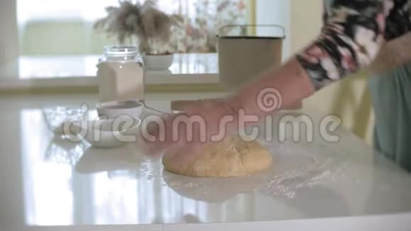 快乐的高级女人在家里厨房里擀比萨饼面团视频的预览图