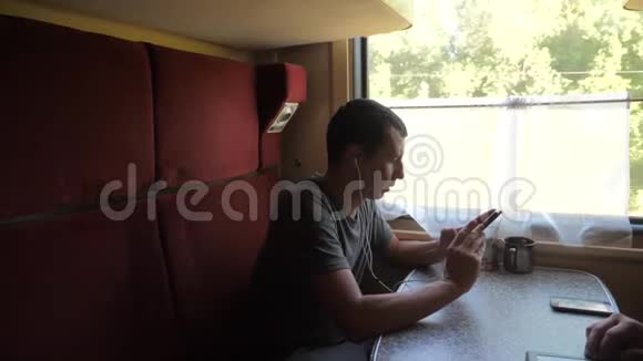 火车车厢上的人的剪影听着耳机上的音乐在信使社交媒体上留言视频的预览图
