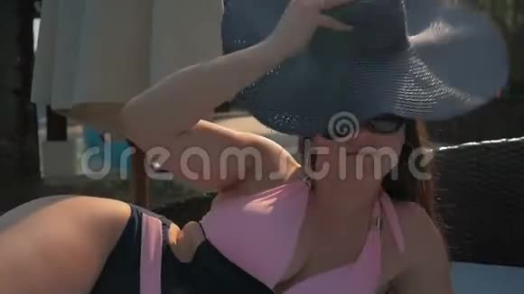 游泳池边的休息室里戴着蓝色帽子的漂亮女孩夏日的阳光视频的预览图