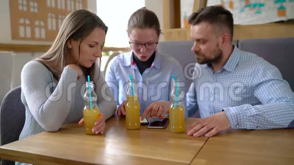 三个朋友坐在咖啡馆里喝果汁在交流中玩得开心视频的预览图