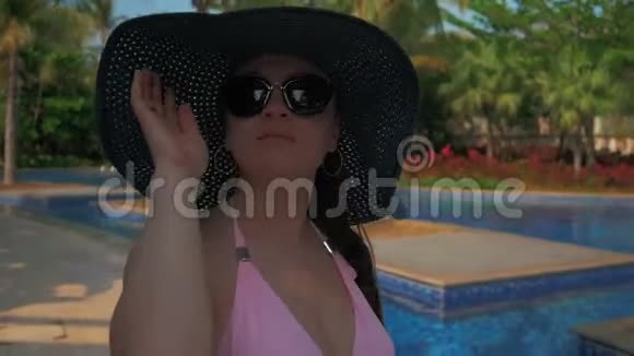 游泳池边的休息室里戴着蓝色帽子的漂亮女孩夏日的阳光视频的预览图