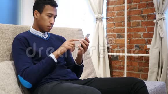 非洲男子在线浏览智能手机使用互联网视频的预览图