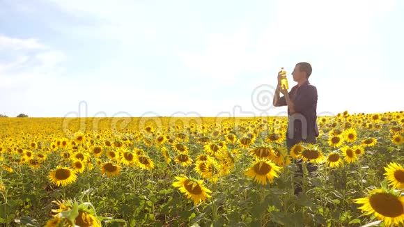 男子农民手捧一瓶葵花籽油在夕阳下的生活方式人类关于葵花籽油生产的节目视频的预览图
