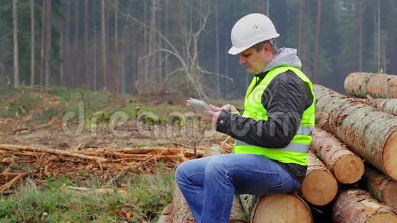 一堆原木上有平板电脑的森林官员视频的预览图