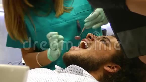 牙医的一个年轻人正在检查他的牙齿视频的预览图
